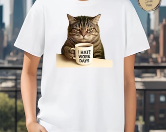 May include: White t-shirt featuring a grumpy-looking tabby cat holding a coffee mug. The mug has the text "I HATE WORK DAYS" printed on it. The cat is brown and black with a serious expression.