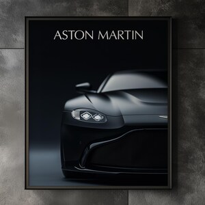 Può includere: Una stampa incorniciata con un'auto Aston Martin nera. Il testo "ASTON MARTIN" è visibile in alto. L'immagine è appesa a una parete grigio scuro in un moderno soggiorno. La parte anteriore dell'auto è in evidenza.