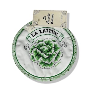 May include: Round white and green pot holder with a green lettuce design and the text "LA LAITUE". The border is green with a leaf pattern. A tag reads "La Grande Cuisine".