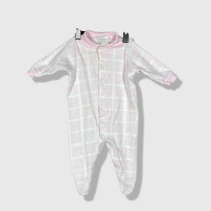May include: A baby's footed sleeper in white with a pink floral pattern. The sleeper has a pink collar and cuffs, and fastens with snaps down the front. The garment is hanging from a hanger.