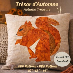 May include: A decorative pillow with a geometric design of a squirrel in shades of orange and brown. The pillow is rectangular and has the text "Trésor d'Automne Autumn Treasure" at the top. The pillow measures 10"-12"-14".