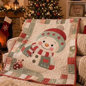 May include: A quilted throw blanket featuring a central applique of a smiling snowman wearing a red and green hat with stars and a striped scarf. The border consists of a patchwork pattern in muted red, green, and cream tones with snowflake motifs.