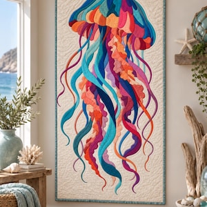 May include: A rectangular fabric wall hanging featuring a vibrant, multi-colored jellyfish appliqué on a cream-colored quilted background. The jellyfish is composed of various shades of blue, purple, orange, and pink fabric pieces.
