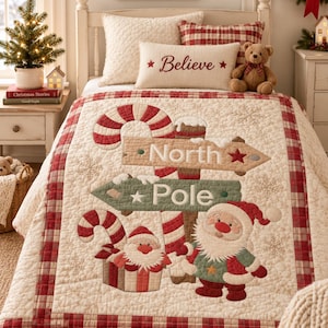 Op de afbeelding: Een crèmekleurige quilt met een Noordpool-wegwijzer, zuurstokken en twee kerstmanfiguren. De quilt heeft een rood-wit geblokte rand en sneeuwvlokpatronen en ligt op een bed met bijpassende kussens en een teddybeer.