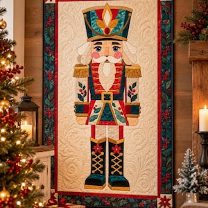 May include: A rectangular wall quilt featuring a central nutcracker figure in a red, blue, and gold uniform. The background is cream with swirling quilted patterns, framed by a border of dark green holly leaves and red berries.