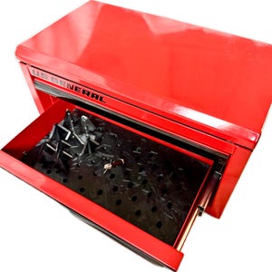 May include: A bright red US GENERAL tool chest with a drawer partially open. The drawer contains a black insert with multiple holes and a key. The tool chest is designed for storing tools and equipment.