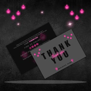 Op de afbeelding: Twee visitekaartjes met een donkergrijze en zwarte achtergrond. De kaarten zeggen "THANK YOU" in grote letters met een roze accent. Eén kaart heeft de tekst "Code: THANKYOU" en "FIND US ONLINE". Roze gloeilampen hangen van boven.