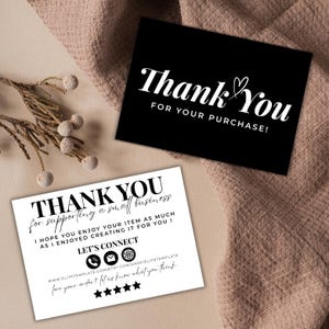 Può includere: Due biglietti con messaggi di "Grazie". Un biglietto è nero con testo bianco, tra cui "PER IL TUO ACQUISTO!". L'altro biglietto è bianco con testo nero, ringraziando i clienti per il supporto a una piccola impresa.