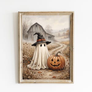 May include: A framed wall art print featuring a white ghost wearing a black witch hat with an orange band, standing next to a carved orange jack-o'-lantern pumpkin. The scene is set on a dirt path in front of a rustic wooden barn in autumn.