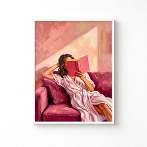 Puede incluir: Una pintura al óleo que muestra a una figura de cabello oscuro con una bata a rayas blancas y rosas, sentada en un sofá rosa intenso mientras lee un libro rosa. El fondo presenta una luz suave que proyecta sombras diagonales en la pared.