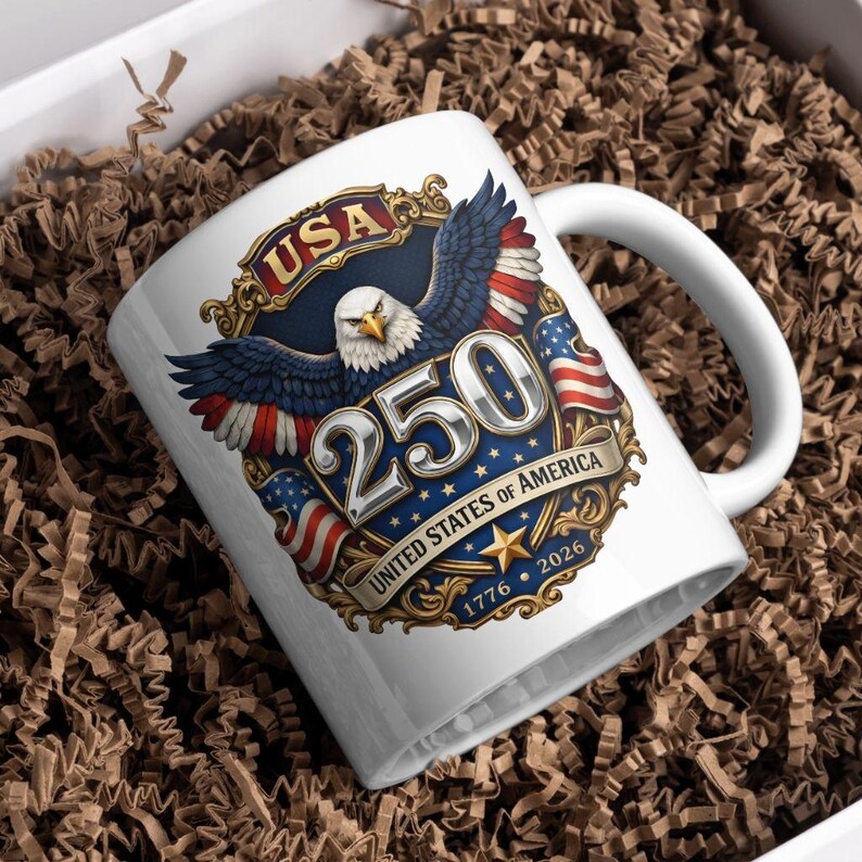 Puede incluir: Taza de cer&aacute;mica blanca con un dise&ntilde;o patri&oacute;tico para el 250 aniversario de los Estados Unidos de Am&eacute;rica. El dise&ntilde;o incluye un &aacute;guila, banderas americanas y el texto "USA 250 United States of America 1776-2026". La taza est&aacute; en una caja de regalo.
