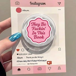 May include: A pink and white phone grip with the text "They Be Fuckin' In This Book" on a pink Instagram-themed background. The image includes social media icons and text, including "520.1314 Likes".