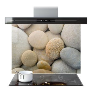 May include: A black range hood with the brand name "PRISMA" and a digital display. The hood is mounted above a glass panel featuring a pebble design. A white saucepan sits on a black hob with four burners.