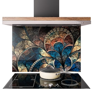 Könnte beinhalten: Eine Küchenabzugshaube mit dekorativer Glasrückwand mit einem farbenfrohen, abstrakten Blumendesign in Blau-, Orange- und Goldtönen. Ein cremefarbener Topf mit silbernem Griff steht auf dem schwarzen Kochfeld.