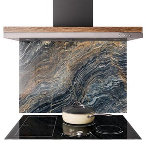 May include: A contemporary kitchen extractor fan above a black hob and a cream-coloured saucepan. The splashback has a marble design with blue, gold, and grey tones. The extractor fan has a wooden trim.