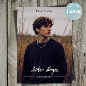 May include: A graduation announcement featuring a young person in a dark sweater and silver chain. The text reads "Class of 2026," "Aiden Hayes," and "St. Joseph High." The background is a blurred outdoor scene with tall grass.