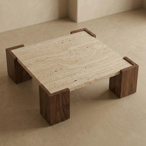 May include: A square coffee table featuring a beige, porous travertine stone top with natural veining. The table is supported by four thick, dark brown wooden legs that wrap around each corner of the stone surface, creating a sturdy frame.