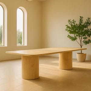 Puede incluir: Una mesa de comedor rectangular de color claro con esquinas redondeadas, sostenida por dos columnas cil&iacute;ndricas y acanaladas. La mesa est&aacute; en una habitaci&oacute;n con ventanas arqueadas y una planta en maceta.