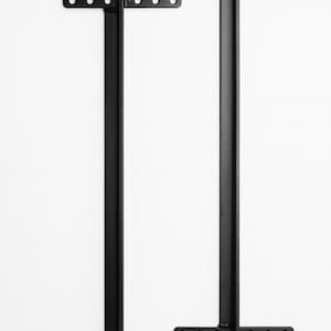 May include: Two black metal table legs. Each leg has a rectangular base with pre-drilled holes for mounting. The legs are T-shaped, with a vertical support and a horizontal base. The legs are designed for furniture construction.