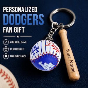 Può includere: Un portachiavi con una mazza da baseball in miniatura in legno incisa con il testo Your Name e un ciondolo a forma di palla da baseball con gessati blu, il logo dei Dodgers e cuciture rosse. Il testo sull'immagine recita PERSONALIZED DODGERS FAN GIFT.