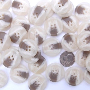 May include: A pile of white and brown striped buttons with four holes each. The buttons are approximately 1 inch in diameter.