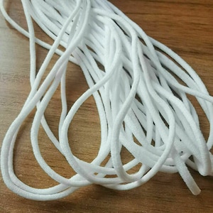 May include: A close-up of a bundle of white elastic cord, commonly used for face masks or other crafts.