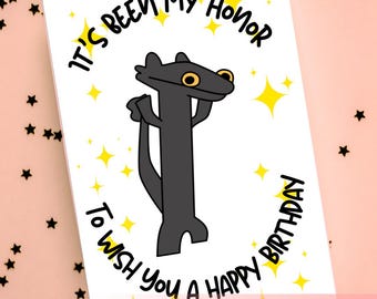 May include: A white birthday card featuring a cartoon black creature with yellow eyes. The card includes the text "It's been my honour to wish you a happy birthday" and "Printable Download". Yellow star graphics are also included.