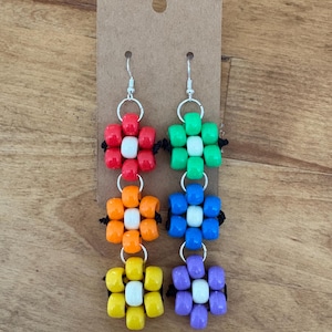 May include: Colorful beaded earrings with a flower design. Each earring features four flower-shaped clusters of beads in red, green, orange, blue, yellow, and purple, with white beads in the center. The earrings hang from silver-colored hooks.