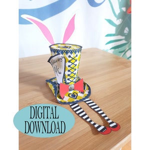 May include: A printable papercraft hat shaped like a top hat with a yellow and blue checkered pattern, white and blue trim, and a red bow. The hat has bunny ears and a tag that says "This is stylish".