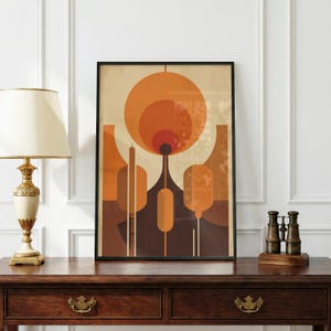 Può includere: Stampa artistica astratta in una cornice nera. L'opera presenta un design retrò con forme geometriche arancioni, marroni e beige. La stampa è esposta su un tavolo di legno scuro con una lampada e un binocolo.