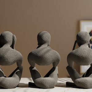 K&ouml;nnte beinhalten: Drei graue abstrakte Skulpturen, die sitzende Figuren in nachdenklicher Pose darstellen. Jede Figur hat eine strukturierte Oberfl&auml;che und ein minimalistisches Design. Die Skulpturen sind in einer Reihe angeordnet, geeignet f&uuml;r die Inneneinrichtung.