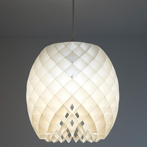 May include: A white, geometric pendant light fixture. The shade is a spherical shape with a diamond pattern. The light hangs from a white cord and a circular ceiling mount. The fixture is illuminated, casting a soft glow.