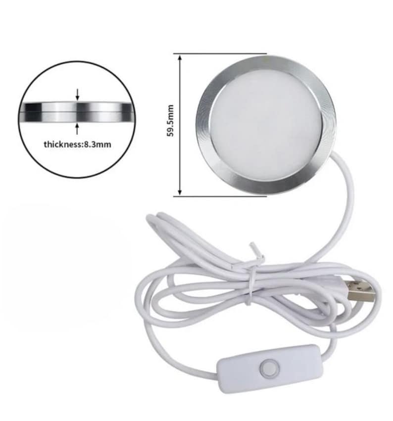 May include: A round, silver LED light with a white center, measuring 59.5mm in diameter and 8.3mm thick. It has a white USB cable with an on/off switch. The light is designed for various applications.