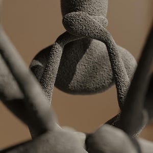 K&ouml;nnte beinhalten: Nahaufnahme einer strukturierten, grauen Skulptur mit einer abgerundeten zentralen Form und gebogenen, armartigen Ausl&auml;ufern. Die Skulptur hat eine raue, k&ouml;rnige Oberfl&auml;che und einen verschwommenen, neutralen Hintergrund.