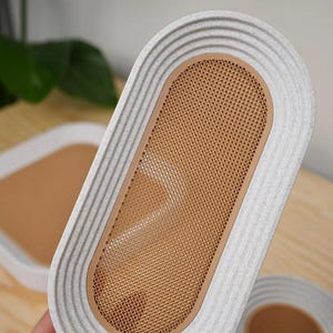 May include: An oval-shaped tray with a textured, light gray border and a tan mesh center. The tray has a ribbed design around the edge. Another tray is visible in the background.