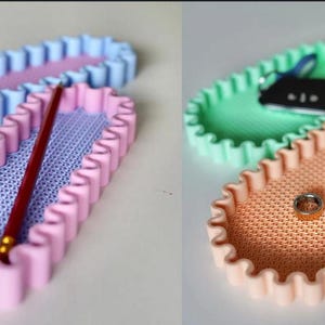 May include: Oval-shaped trays in pastel colors. One pink tray holds a red pencil. Another tray is light blue. A third tray is peach-colored, holding a ring and a white case. A green tray holds keys.