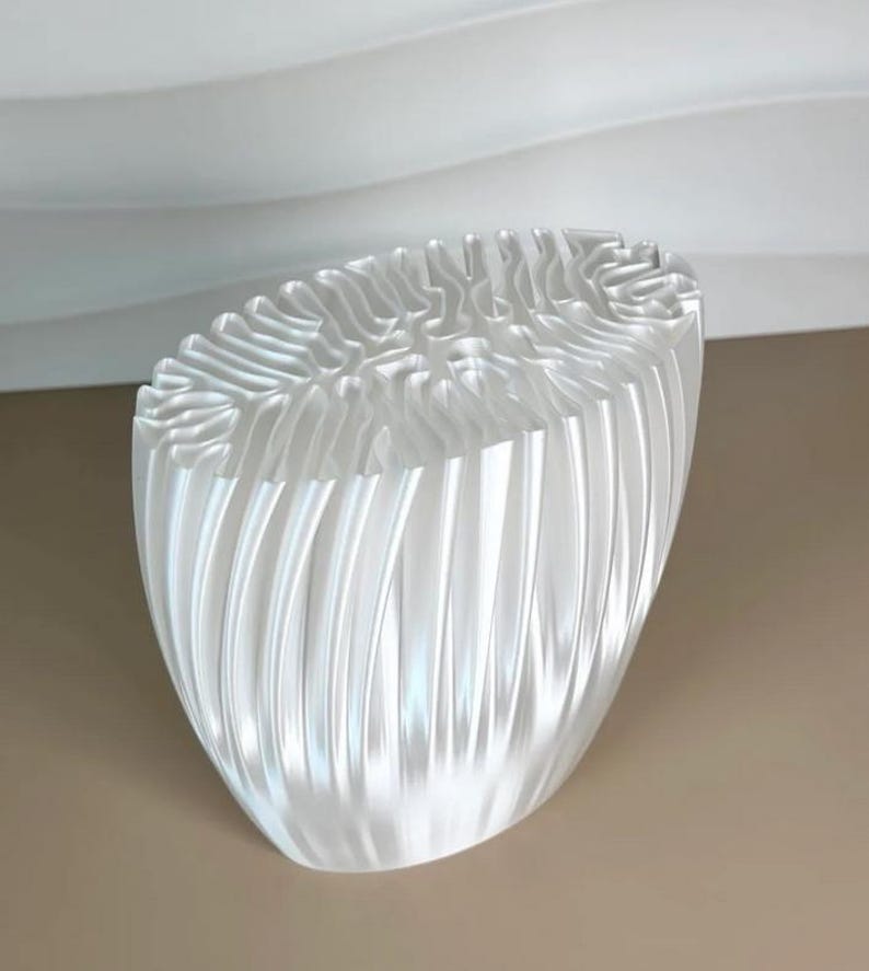 May include: A translucent, oval-shaped decorative bowl with a textured, ridged exterior. The bowl's design features vertical, wave-like patterns that create a sense of depth and light reflection. The interior has a unique, organic texture.