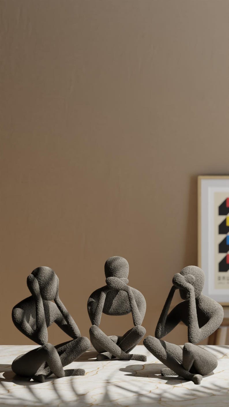 K&ouml;nnte beinhalten: Drei graue abstrakte Skulpturen von sitzenden Figuren, jede in einer anderen Pose, die ihre Augen, Ohren oder ihren Mund bedecken. Die Figuren stehen auf einer marmor&auml;hnlichen Oberfl&auml;che mit neutralem braunem Hintergrund.