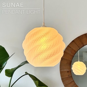 May include: A white spherical pendant light with a textured, swirling pattern on its surface. The light is suspended by a thin cord. The text SUNAE PENDANT LIGHT is visible in the upper left corner. The light is reflected in a circular mirror.