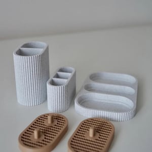 May include: A set of six speckled, textured bathroom or desk organizers in shades of gray and brown. The set includes a tall, divided cylinder, a smaller divided organizer, a tray with three compartments, and two soap dishes.