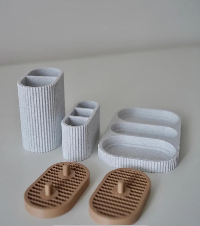 May include: A set of six speckled, textured bathroom or desk organizers in shades of gray and brown. The set includes a tall, divided cylinder, a smaller divided organizer, a tray with three compartments, and two soap dishes.