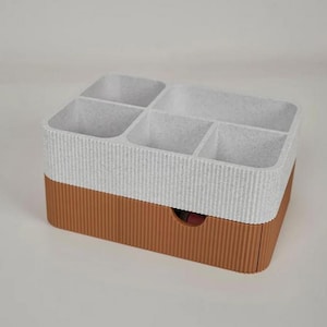 May include: A two-tone organizer with a textured, ribbed design. The top section is white with multiple compartments, while the bottom is brown with a small drawer. Ideal for storing small items.