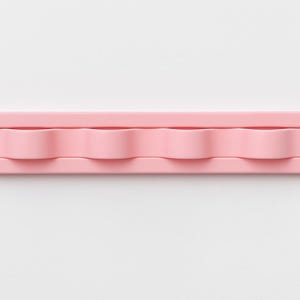 May include: A light pink, rectangular wall-mounted hook rack featuring four rounded, wave-shaped hooks integrated into a single, smooth, elongated base with rounded ends, designed for organizing small items in a clean, uniform arrangement.