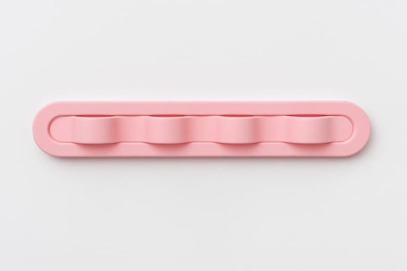 May include: A light pink, rectangular wall-mounted hook rack featuring four rounded, wave-shaped hooks integrated into a single, smooth, elongated base with rounded ends, designed for organizing small items in a clean, uniform arrangement.