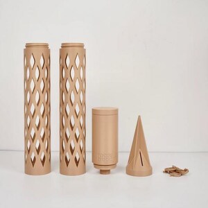 May include: A collection of beige-colored, decorative items. Two tall, cylindrical pieces with diamond-shaped cutouts stand beside a shorter cylinder with the text "moss buddy". A conical shape and small wooden pieces complete the set.