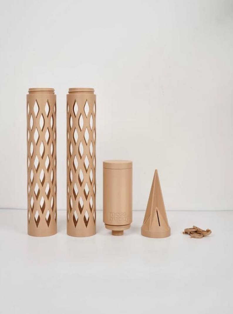 May include: A collection of beige-colored, decorative items. Two tall, cylindrical pieces with diamond-shaped cutouts stand beside a shorter cylinder with the text "moss buddy". A conical shape and small wooden pieces complete the set.