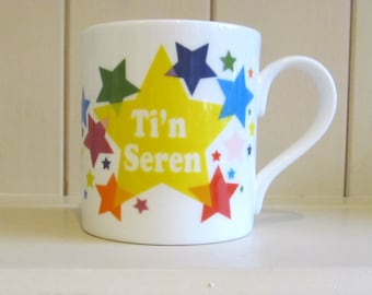 Welsh language mug featuring the words 'Ti'n Sere'n meaning' Your a Star' with a beautiful stream of multi coloured stars.