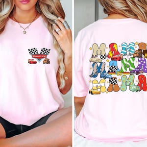 May include: Light pink t-shirt featuring a front pocket design with checkered flags and cartoon cars. The back of the shirt displays the word "MAMA" in a colorful, playful font, with car illustrations and the number "95".