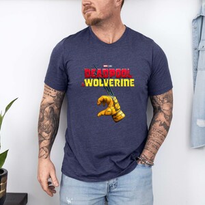 Puede incluir: Camiseta azul marino con cuello en V con el texto "DEADPOOL WOLVERINE" en rojo y amarillo. La camiseta tiene un gr&aacute;fico de un guante amarillo con garras. La camiseta est&aacute; hecha de un material suave y c&oacute;modo.