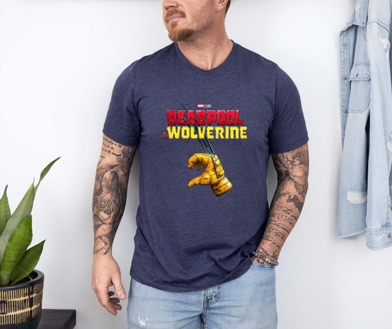 Puede incluir: Camiseta azul marino con cuello en V con el texto "DEADPOOL WOLVERINE" en rojo y amarillo. La camiseta tiene un gr&aacute;fico de un guante amarillo con garras. La camiseta est&aacute; hecha de un material suave y c&oacute;modo.